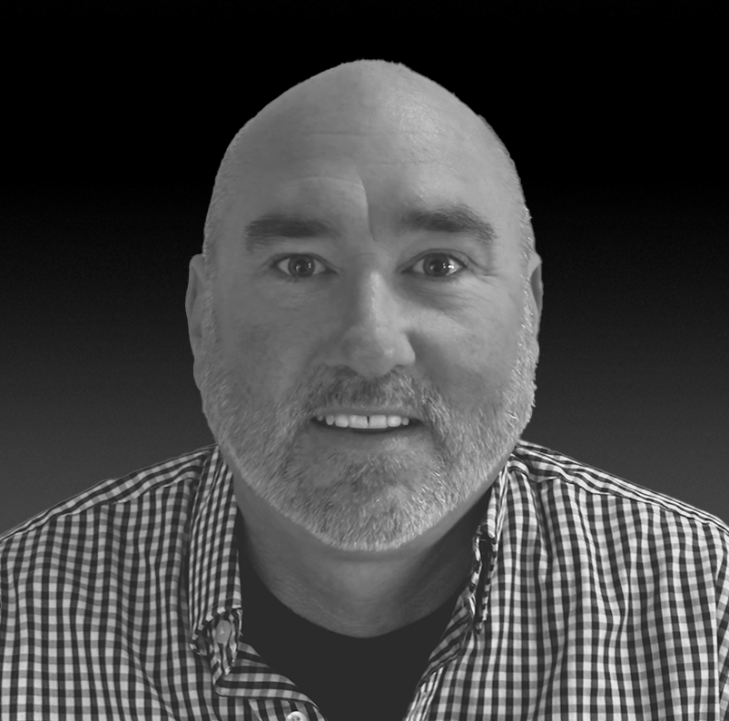 A black and white photo of Bill Graham, smiling and looking directly at the camera.