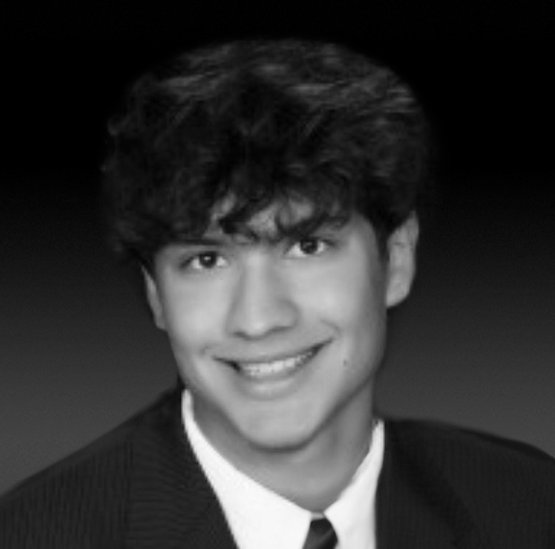 A black and white photo of Liam Rogers, smiling and looking directly at the camera.